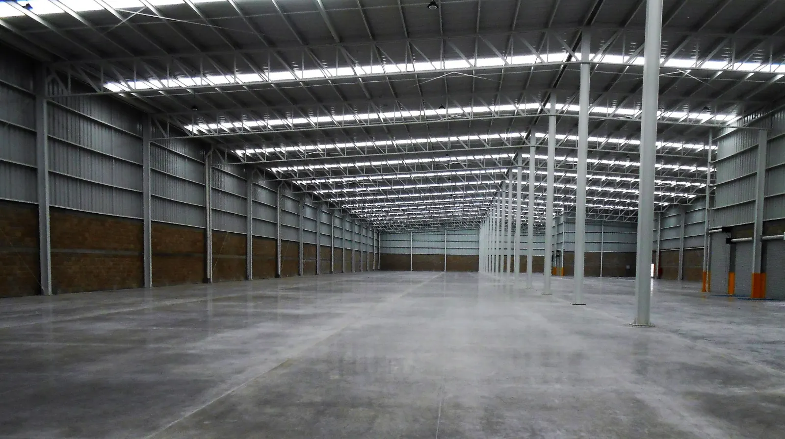 Interior de nave industrial nueva con estructura de acero e iluminación natural, referencia del desarrollo Eje 132